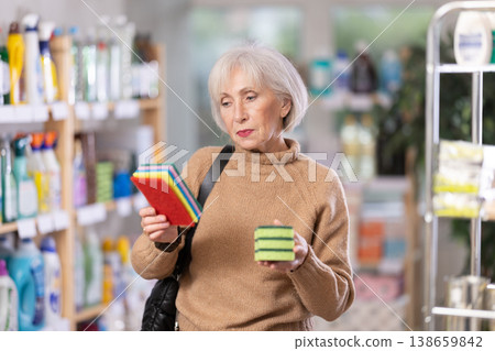 Mature woman choosing cleaning sponge in department store Mature woman choosing cleaning sponge in department store 138659842