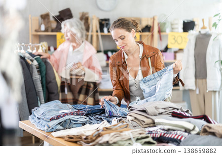 woman chooses jeans against the background of an elderly customer 138659882