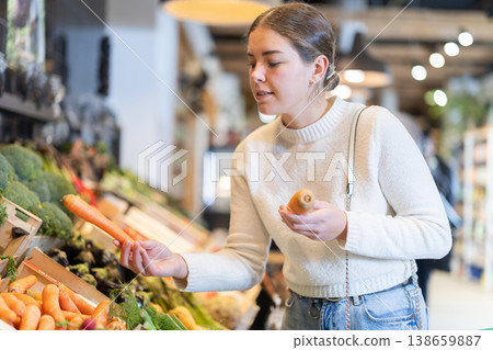 Young woman choosing carrots in grocery supermarket 138659887