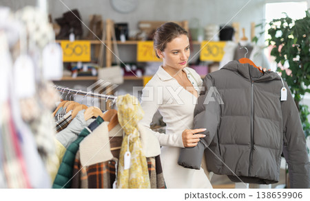 Young woman chooses sweater in clothing store 138659906