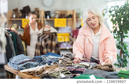 Elderly woman choosing sweaters against the background of female buyer Elderly woman choosing sweaters against the background of female buyer 138659907