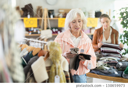 Elderly woman choosing gloves in clothing store Elderly woman choosing gloves in clothing store 138659973