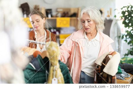 woman, together with a mature woman, chooses outerwear woman, together with a mature woman, chooses outerwear 138659977