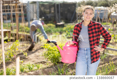 Portrait of an satisfied woman with watering can for watering plants in garden 138660087