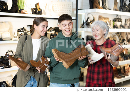 Guy and two women choose boots in store Guy and two women choose boots in store 138660091