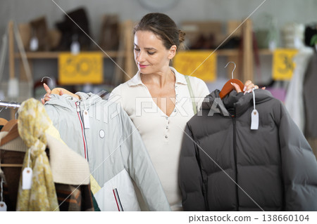 Woman choosing a down jacket in a clothing store Woman choosing a down jacket in a clothing store 138660104