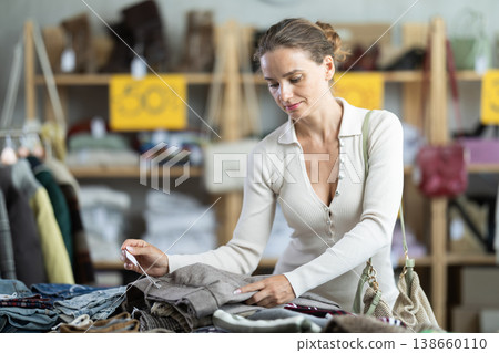 European woman customer examine and choose trousers in store 138660110