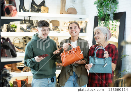 Mature woman sales consultant helps couple customers decide on choice of model handbag 138660114