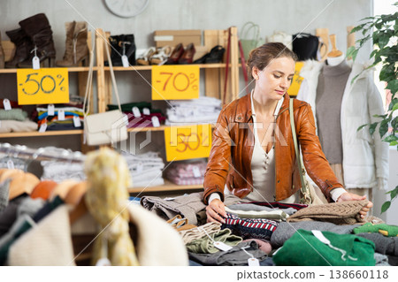 Young woman chooses sweater in clothing store Young woman chooses sweater in clothing store 138660118