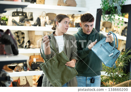 Young man with girl friend inspects shop window and is looking for modern handbag Young man with girl friend inspects shop window and is looking for modern handbag 138660200