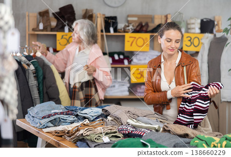 Adult woman choosing sweaters against the background of pensioner buyer Adult woman choosing sweaters against the background of pensioner buyer 138660229