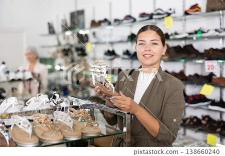 Young woman chooses sandals in shoe store Young woman chooses sandals in shoe store 138660240
