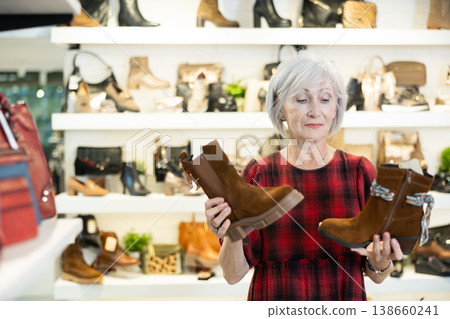 Contemplative elderly woman choosing demi-season boots in shoe store 138660241