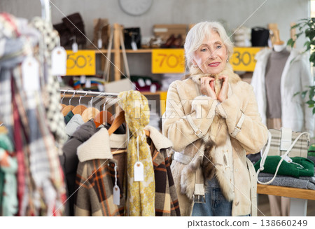 Senior woman chooses and try on fur jacket in store Senior woman chooses and try on fur jacket in store 138660249