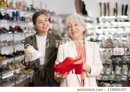 Mom with an adult daughter choose and buy fashionable high heeled shoes in a shoe store 138660267