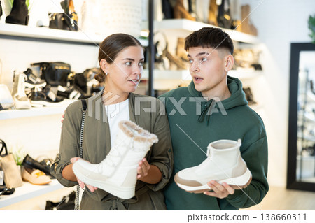 Young couple discussing choice of winter womens boots in shoe store Young couple discussing choice of winter womens boots in shoe store 138660311