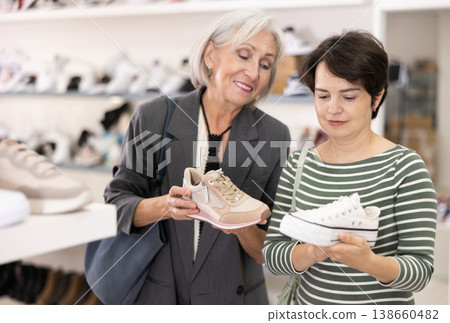 Adult and elderly women choosing sneakers in store Adult and elderly women choosing sneakers in store 138660482