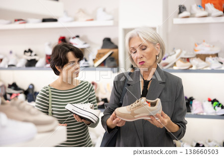 Two women are shopping in shoe store, choose snickers Two women are shopping in shoe store, choose snickers 138660503