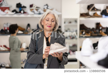Elderly woman chooses sneakers in shoe store 138660506