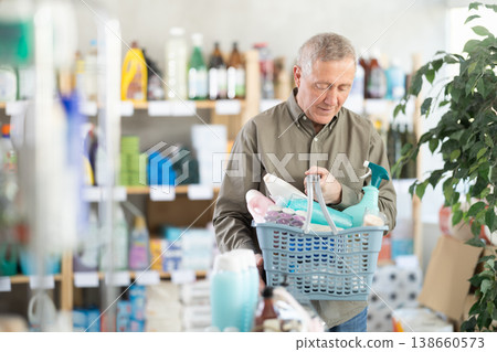 Man with a full basket of goods in a household chemicals store Man with a full basket of goods in a household chemicals store 138660573