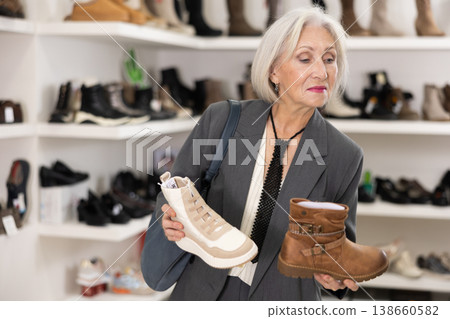 Elderly woman chooses boots in shoe store 138660582