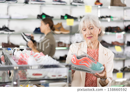 In multi-brand leather goods store,senior lady chooses modern comfortable running sneakers for fitness In multi-brand leather goods store,senior lady chooses modern comfortable running sneakers for fitness 138660592