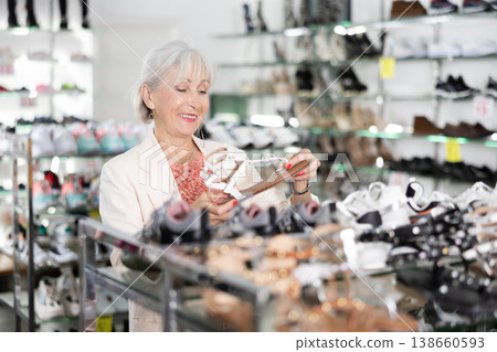 Mature woman who came to shoe store for shopping, chooses summer shoes 138660593