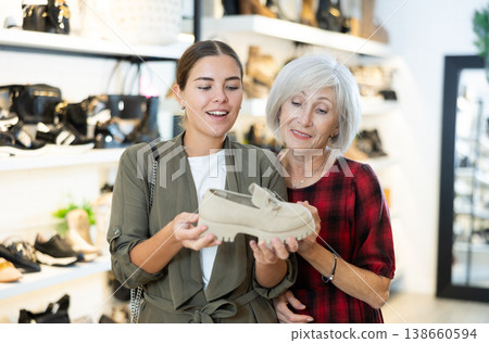 Elderly mother with young daughter view moccasins in footwear store Elderly mother with young daughter view moccasins in footwear store 138660594