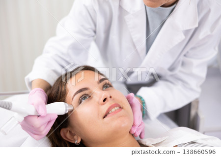Elderly female beautician doing procedure of microneedling, mesotherapy for young woman in beauty salon indoors 138660596