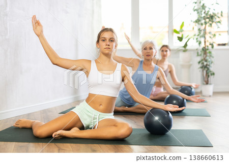 Family grandmother, mother and granddaughter perform fitness exercise sitting on floor with softball 138660613