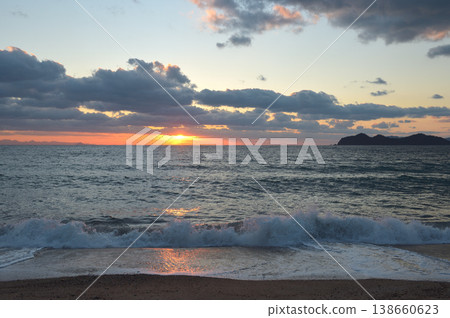 冬日里,白色的海浪拍打著室住在海岸。夕陽透過雲層灑下斑駁的光影。 (山口縣光市) 冬日里,白色的海浪拍打著室住在海岸。夕陽透過雲層灑下斑駁的光影。 (山口縣光市) 138660623