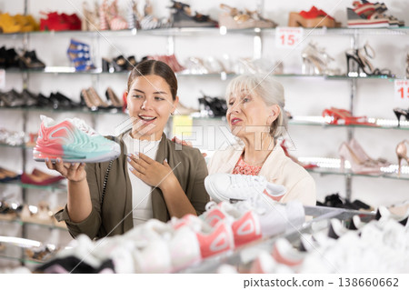Young colleague shows elderly lady advantages of thick sole in modern sneakers Young colleague shows elderly lady advantages of thick sole in modern sneakers 138660662