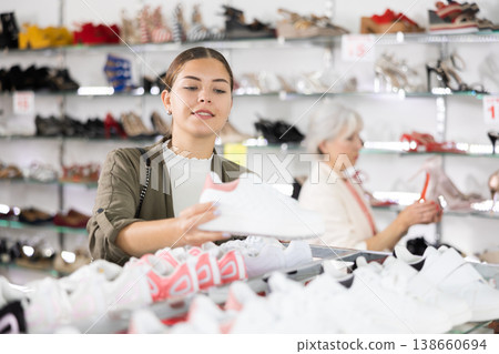 Young woman chooses sneakers in shoe store 138660694