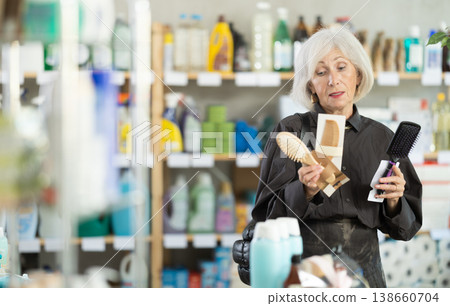 Female shopper chooses best comb in household supermarket 138660704