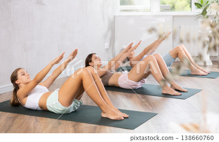 Teen girl doing crunches during group yoga training in fitness studio Teen girl doing crunches during group yoga training in fitness studio 138660760