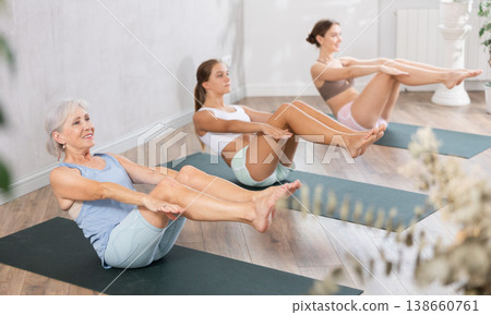 Three generation of women perform sitting lightweight variation of boat pose Paripurna Navasana Three generation of women perform sitting lightweight variation of boat pose Paripurna Navasana 138660761