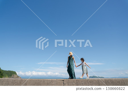 一位家長和孩子手牽手走在沙灘上。 138660822