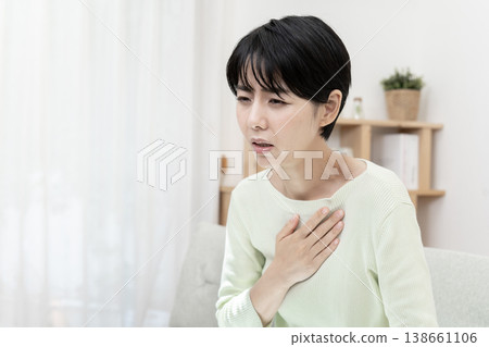 A woman clutches her chest, suddenly feeling unwell; chest pain, stress. A woman clutches her chest, suddenly feeling unwell; chest pain, stress. 138661106