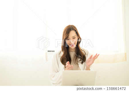 一位女士上網聊天時,筆記型電腦放在腿上。 一位女士上網聊天時,筆記型電腦放在腿上。 138661472