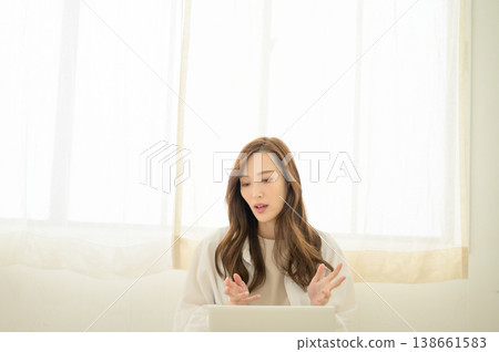 A woman with her laptop on her lap during an online conversation. A woman with her laptop on her lap during an online conversation. 138661583