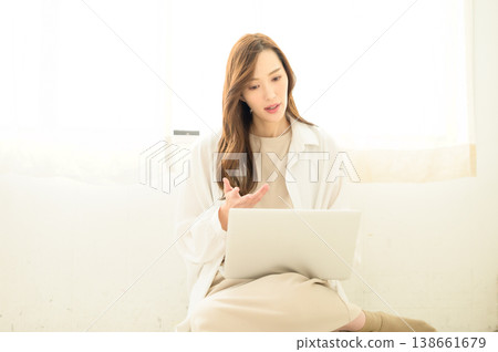 一位女士將筆記型電腦放在腿上使用。 138661679