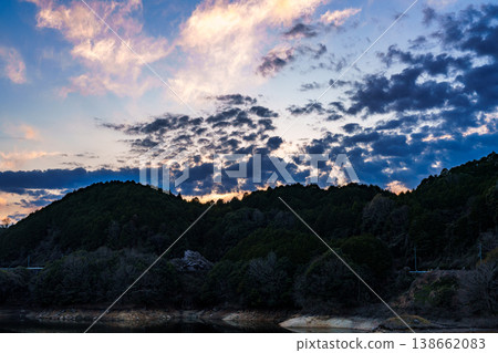 Spring 2026, after sunset: A beautiful sunset sky above Lake Nunome, with scattered dark clouds near the mountains and crimson clouds in the sky. Spring 2026, after sunset: A beautiful sunset sky above Lake Nunome, with scattered dark clouds near the mountains and crimson clouds in the sky. 138662083