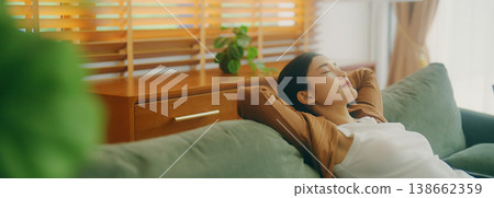 Relaxed young Asian woman enjoying rest on comfortable sofa 138662359