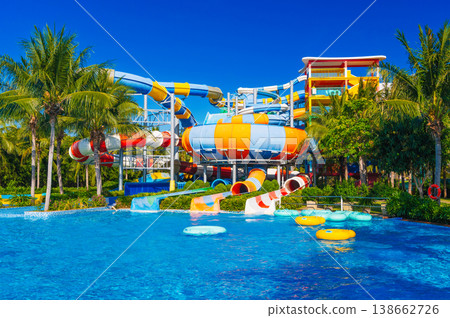 water park with slides and pipes for active extreme recreation at the resort in summer. Big colorful aquapark with a pool in the tropics 138662726