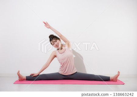 A yoga image showing a woman stretching her side while doing a split, improving flexibility, and a full-body front view. 138663242
