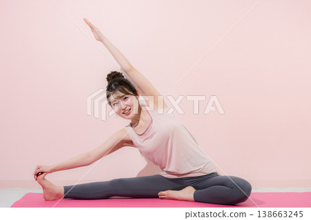 一位女性在做劈腿時伸展側腰,這是一張瑜珈圖片,旨在提高柔韌性,全身照,直視鏡頭。 一位女性在做劈腿時伸展側腰,這是一張瑜珈圖片,旨在提高柔韌性,全身照,直視鏡頭。 138663245