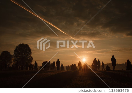 Spectators Silhouetted Against Sunset Watching Rocket Lift Off into the Sky 138663476