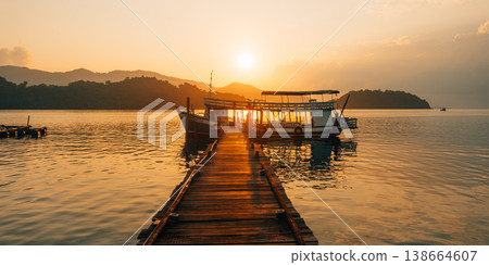 Traditional Thai wooden fishing boat moored at a pier during a golden sunset. 138664607