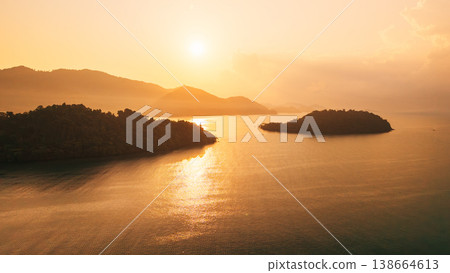 Aerial view of tropical islands and ocean during a vibrant golden sunrise. Aerial view of tropical islands and ocean during a vibrant golden sunrise. 138664613