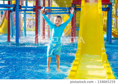 Caucasian happy playful child boy enjoy and has fun at water park in summer on vacation. Children's aquapark with water slide and swimming pool in resort Caucasian happy playful child boy enjoy and has fun at water park in summer on vacation. Children's aquapark with water slide and swimming pool in resort 138665259